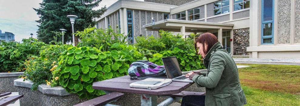在费尔班克斯西岭校区外的一张桌子上，她正在用笔记本电脑工作